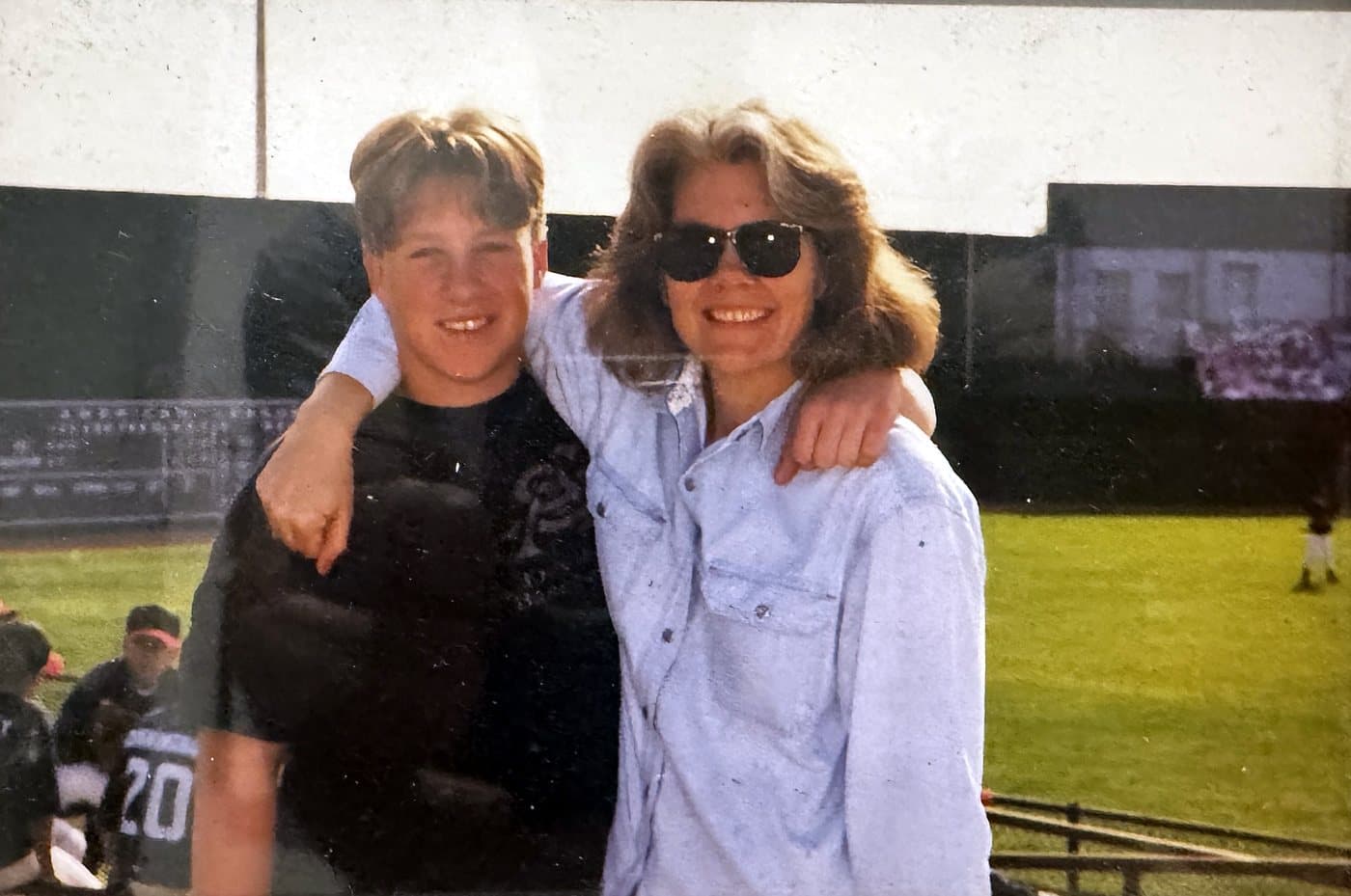 Isaac's brother, Garrett, with his arm around their mom, Eve, at a baseball field