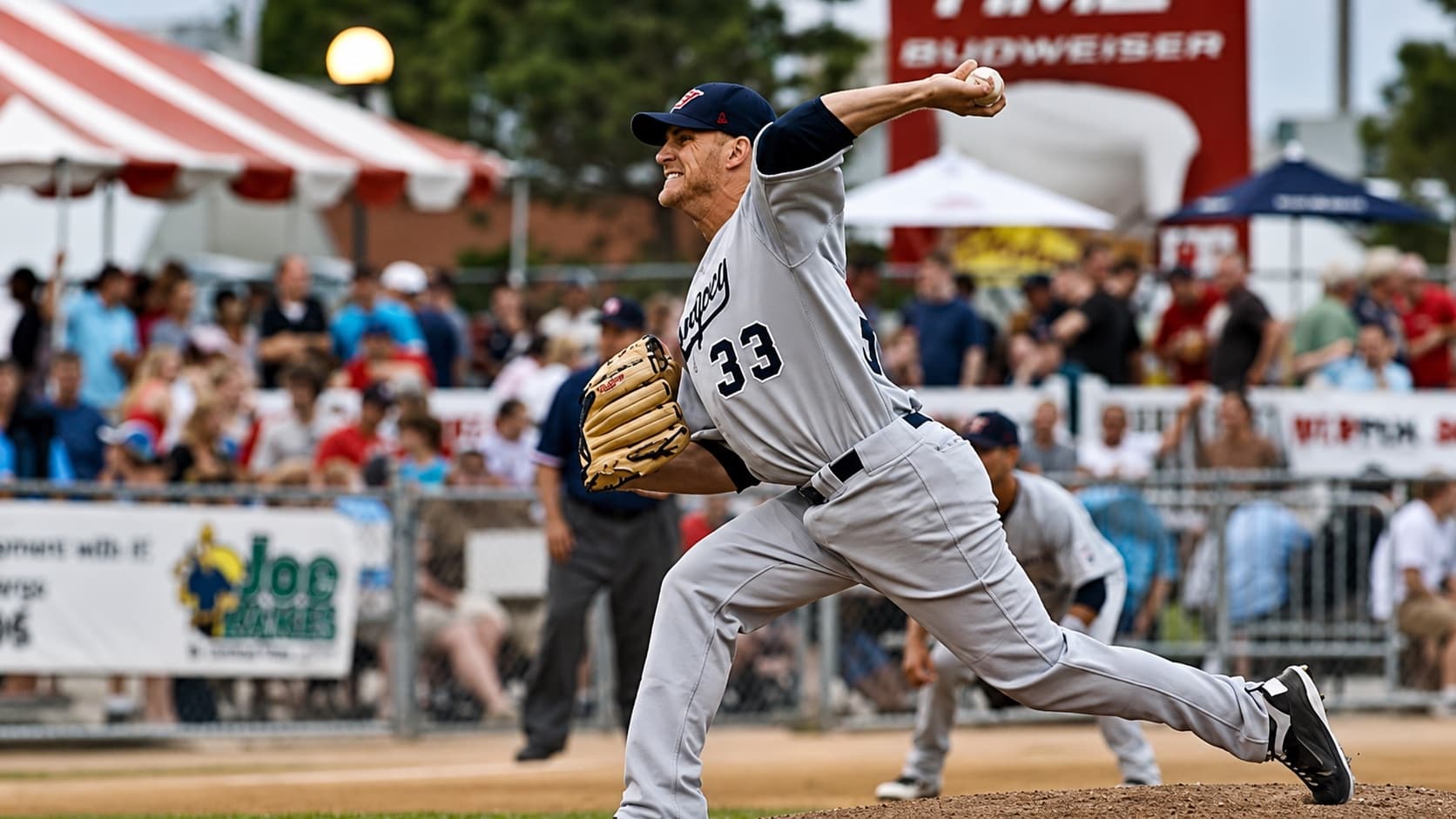 Isaac Hess mid-delivery in road greys, number 33